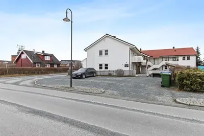 a street with a car parked next to a white house at Nyoppusset leilighet midt i sentrum in Verdal