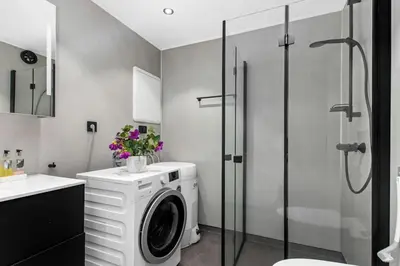 a washing machine in a bathroom with a shower at Nyoppusset leilighet midt i sentrum in Verdal