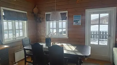 a dining room with a table and chairs and windows at Hytte i Myrkdalen in Helgatun