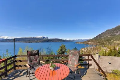 a table and chairs on a deck with a view of a lake at Cozy cabin, minimum 5 nights in Oppheim