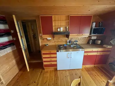 a kitchen with red cabinets and a sink in a cabin at Cozy cabin, minimum 5 nights in Oppheim