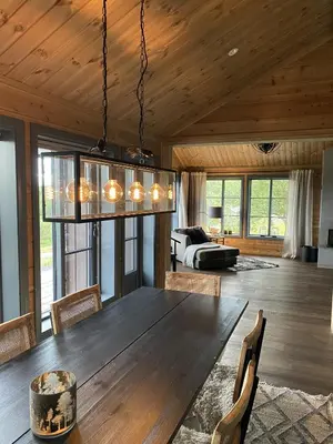 a dining room with a wooden table and a chandelier at New, cozy, and comfortable cabin in Geilo in Flatåker