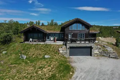a large wooden house with a garage on a hill at New, cozy, and comfortable cabin in Geilo in Flatåker