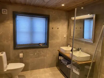 a bathroom with a toilet and a sink and a mirror at New, cozy, and comfortable cabin in Geilo in Flatåker