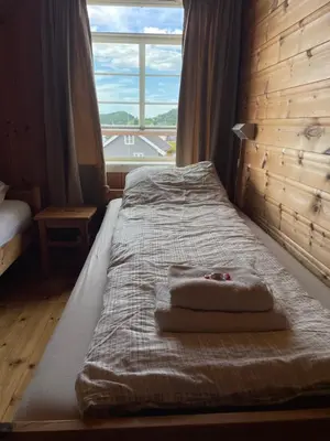 a bed with a towel on it in front of a window at Vågen Fjordbuer - Snekkerbua in Ravlo
