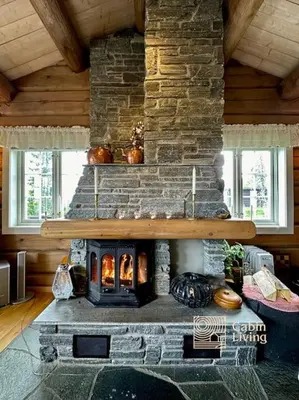 a living room with a stone fireplace in a house at Large log cabin at Sjusjøen with sauna, fireplace and panoramic view in Ringsaker