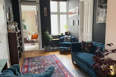 a living room with a blue couch and a rug at Spacious historical art oasis in the city center in Bergen