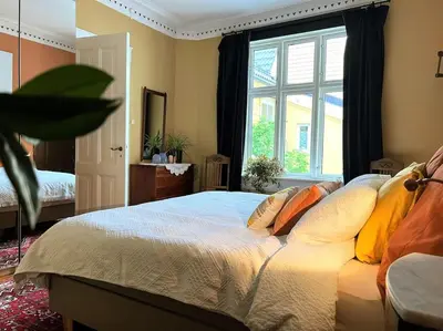 a bedroom with a bed with pillows and a window at Spacious historical art oasis in the city center in Bergen