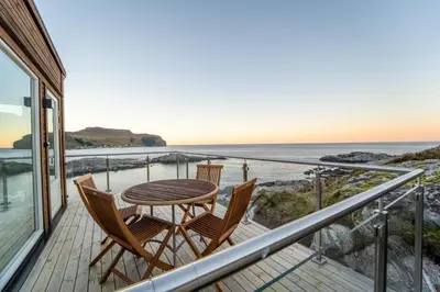a balcony with a table and chairs overlooking the ocean at Runde Panorama - Eden in Runde