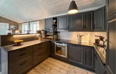 a kitchen with black cabinets and a wooden floor at Amazing Home In Sjusjøen With Sauna in Sjusjøen