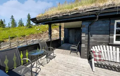 a deck with chairs and a table and a building with a grass roof at Amazing Home In Sjusjøen With Sauna in Sjusjøen