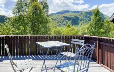 two chairs and a table on a deck with mountains at 2 Bedroom Pet Friendly Home In Haddal in Haddal