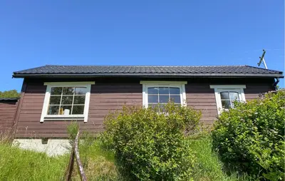 a brown house with white windows and some bushes at 2 Bedroom Pet Friendly Home In Haddal in Haddal
