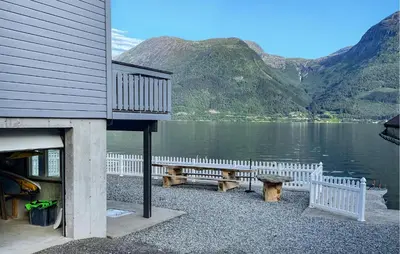 a building with a bench next to a body of water at Stunning Home In Vallavik With Wifi in Djønno