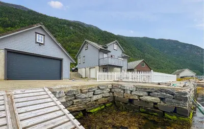 a house with a garage and a stone wall at Stunning Home In Vallavik With Wifi in Djønno