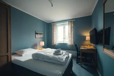 a blue bedroom with a bed and a window at Gålå Høgfjellshotell in Gålå