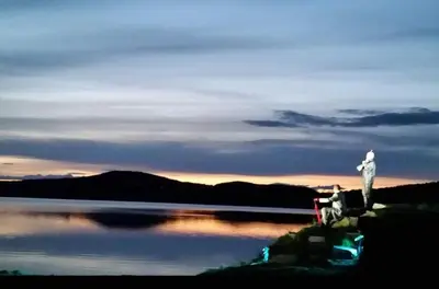 a person standing on the edge of a body of water at Gålå Høgfjellshotell in Gålå