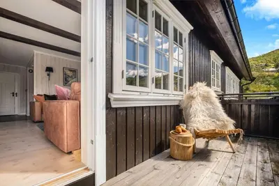 a dog sitting on a bench on the porch of a house at Gaustatoppen View Apartment in Gaustablikk
