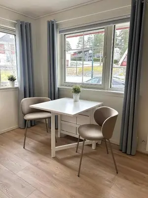 a white table and chairs in a room with windows at Newly renovated studio apartment - free parking and EV docking in Trondheim