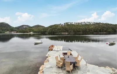 a dock with tables and chairs on a lake at Stunning Home In Førde I Hordaland in Erve