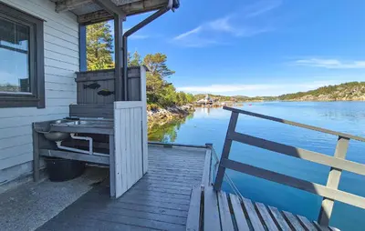 a house with a grill on the side of the water at Lovely Home In Urangsvåg in Steinsbø