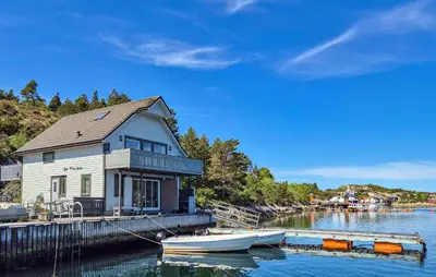 a boat is docked next to a house on the water at Lovely Home In Urangsvåg in Steinsbø