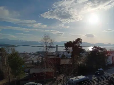 a view of a body of water with the sun at Sentralt, kort vei til byens fasiliteter in Molde