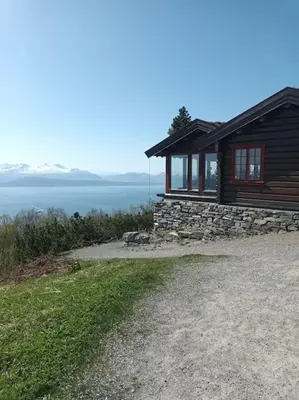 a small cabin with a stone wall next to the water at Sentralt, kort vei til byens fasiliteter in Molde