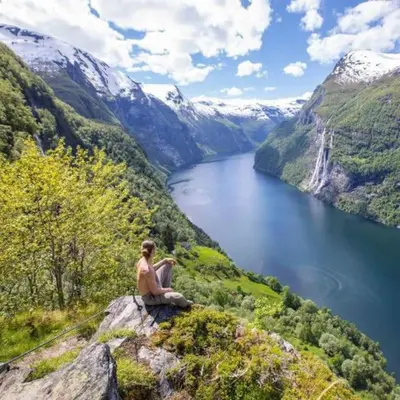 a man sitting on top of a mountain overlooking a lake at Sentralt, kort vei til byens fasiliteter in Molde