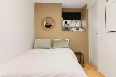 a bedroom with a white bed and a mirror at Dinbnb Apartments I Cobblestone Streets 350m from Bryggen & Fløybanen! in Bergen