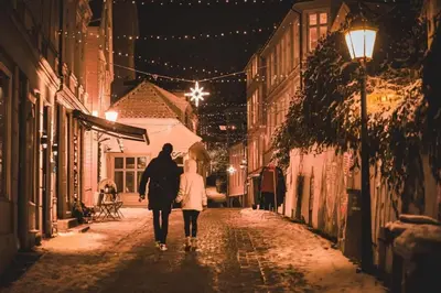 a man and woman walking down a street at night at Dinbnb Apartments I Cobblestone Streets 350m from Bryggen & Fløybanen! in Bergen
