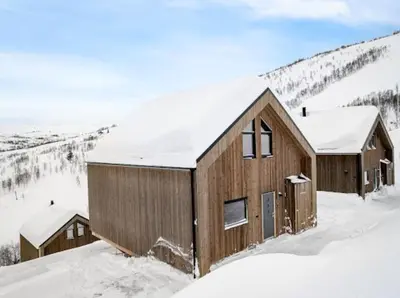 a wooden cabin in the snow with snow covered mountains at Flygende utsiktshytte med magisk utsikt in Sogndal