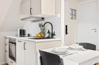 a kitchen with white cabinets and a table with chairs at View to Bryggen - Renovated dec 24 - Historic cobblestone street in Bergen