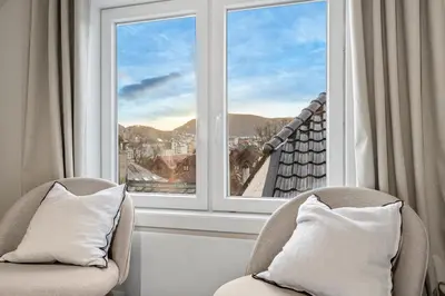 a room with two chairs and a large window at View to Bryggen - Renovated dec 24 - Historic cobblestone street in Bergen