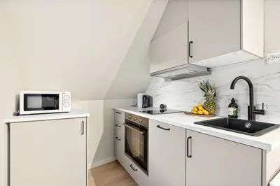 a white kitchen with a sink and a microwave at View to Bryggen - Renovated dec 24 - Historic cobblestone street in Bergen