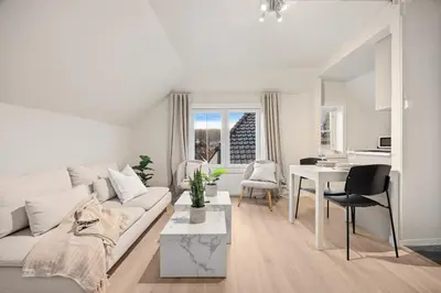 a white living room with a white couch and a table at View to Bryggen - Renovated dec 24 - Historic cobblestone street in Bergen