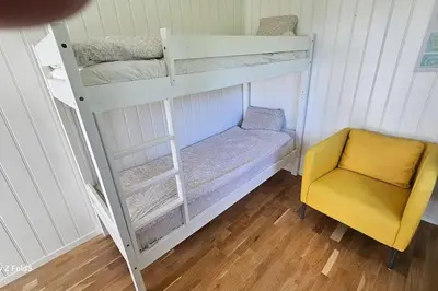 a bedroom with two bunk beds and a yellow chair at Koselig hytte på Austrheim