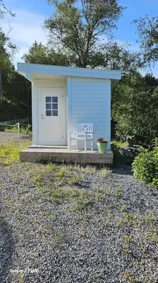 a small shed with a white bench in a yard at Koselig hytte på Austrheim