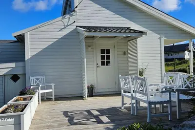 a group of white chairs sitting on a patio at Koselig hytte på Austrheim