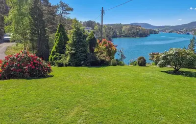 a green lawn with a view of a lake at 4 Bedroom Awesome Home In Ølve in Ølve