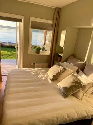 a large white bed with pillows in a bedroom at seaside house with stunning sunsets & sun all day Near Trondheim in Buvika