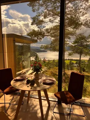 a table and chairs in a room with a large window at Speilsuite med egen badstue og panorama in Steinkjer
