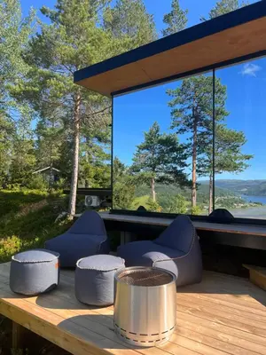a wooden table with chairs on a deck with a large window at Speilsuite med egen badstue og panorama in Steinkjer