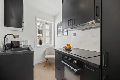 a kitchen with black cabinets and a sink at Homerentals Apartments - Behind Bryggen & historic cobblestone streets - 2 Floor renovated from february 2025 in Bergen