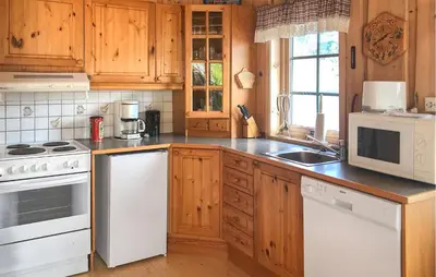 a kitchen with white appliances and wooden cabinets at Stunning Home In Lauvstad With House Sea View in Lauvstad