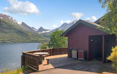 a cabin with a deck next to a lake at Stunning Home In Lauvstad With House Sea View in Lauvstad