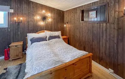 a bedroom with a bed in a wooden wall at 3 Bedroom Lovely Home In Sjusjøen in Sjusjøen