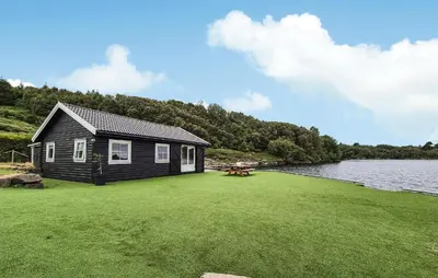 a house on a lawn next to a body of water at 2 Bedroom Lovely Home In Haugesund in Haugesund