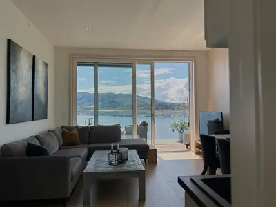 a living room with a couch and a large window at MJOS TOWER - Balcony Suite with lake view in Ringsaker