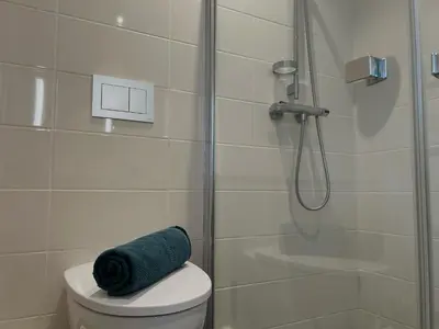 a bathroom with a shower and a blue towel on a toilet at MJOS TOWER - Balcony Suite with lake view in Ringsaker